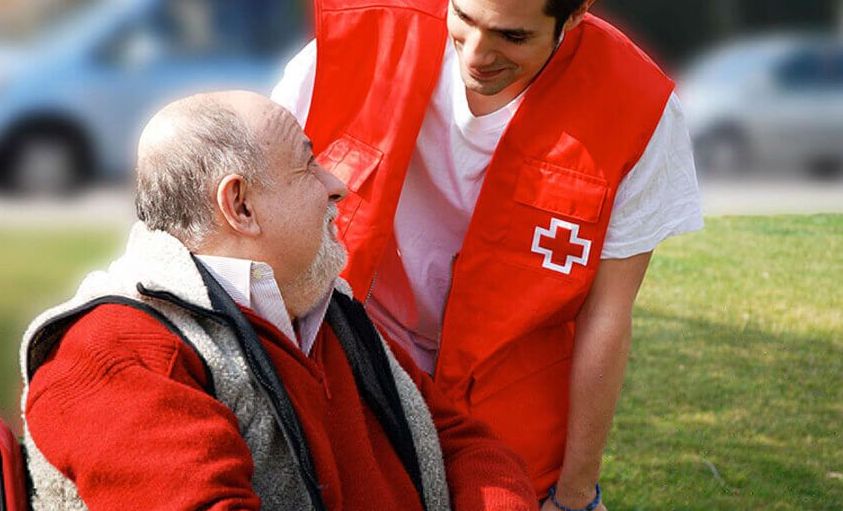 Voluntario de Cruz Roja acompañando a una persona mayor